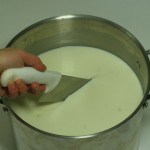 Knife cutting curd in pot