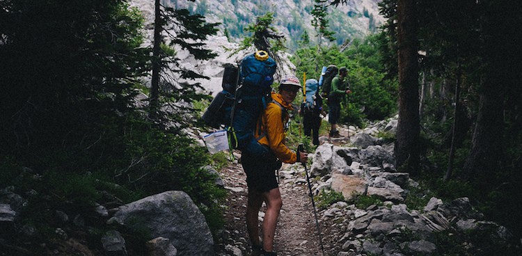 three backpackers hiking on a mountain path