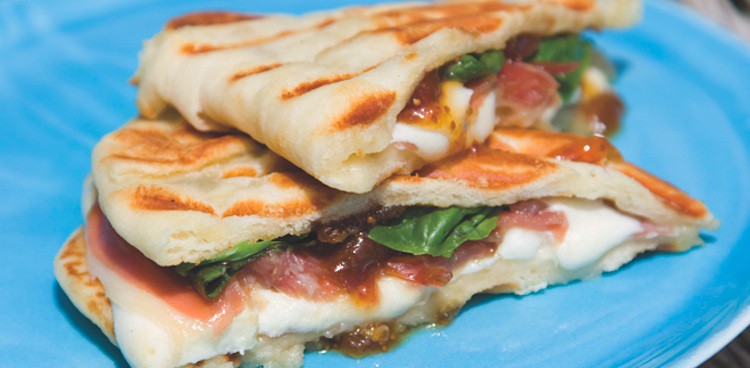 grilled pita sandwich with prosciutto, fig, greens, and mozzarella