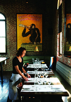 A waitress sets the table in a dark dining room