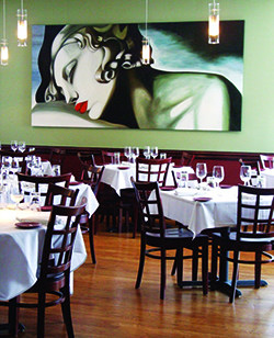 An empty dining room with an art deco painting of a woman