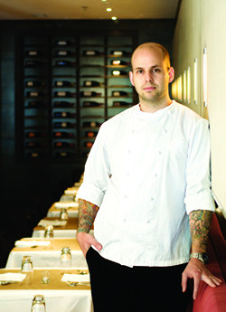 A chef stands against a wall