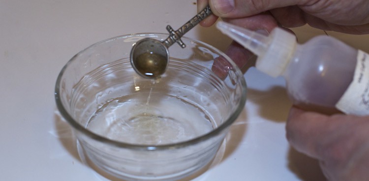 liquid rennet being diluted in custard cup of water