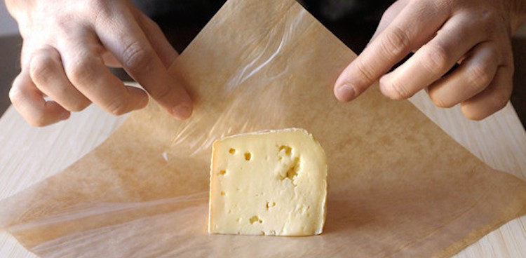 cheese being wrapped in brown formaticum paper