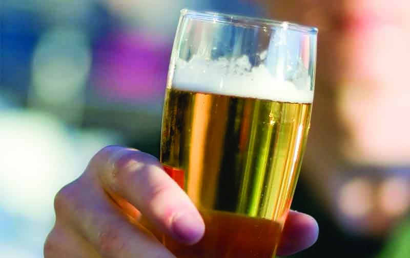 A man holds up a pint of a bière de garde.