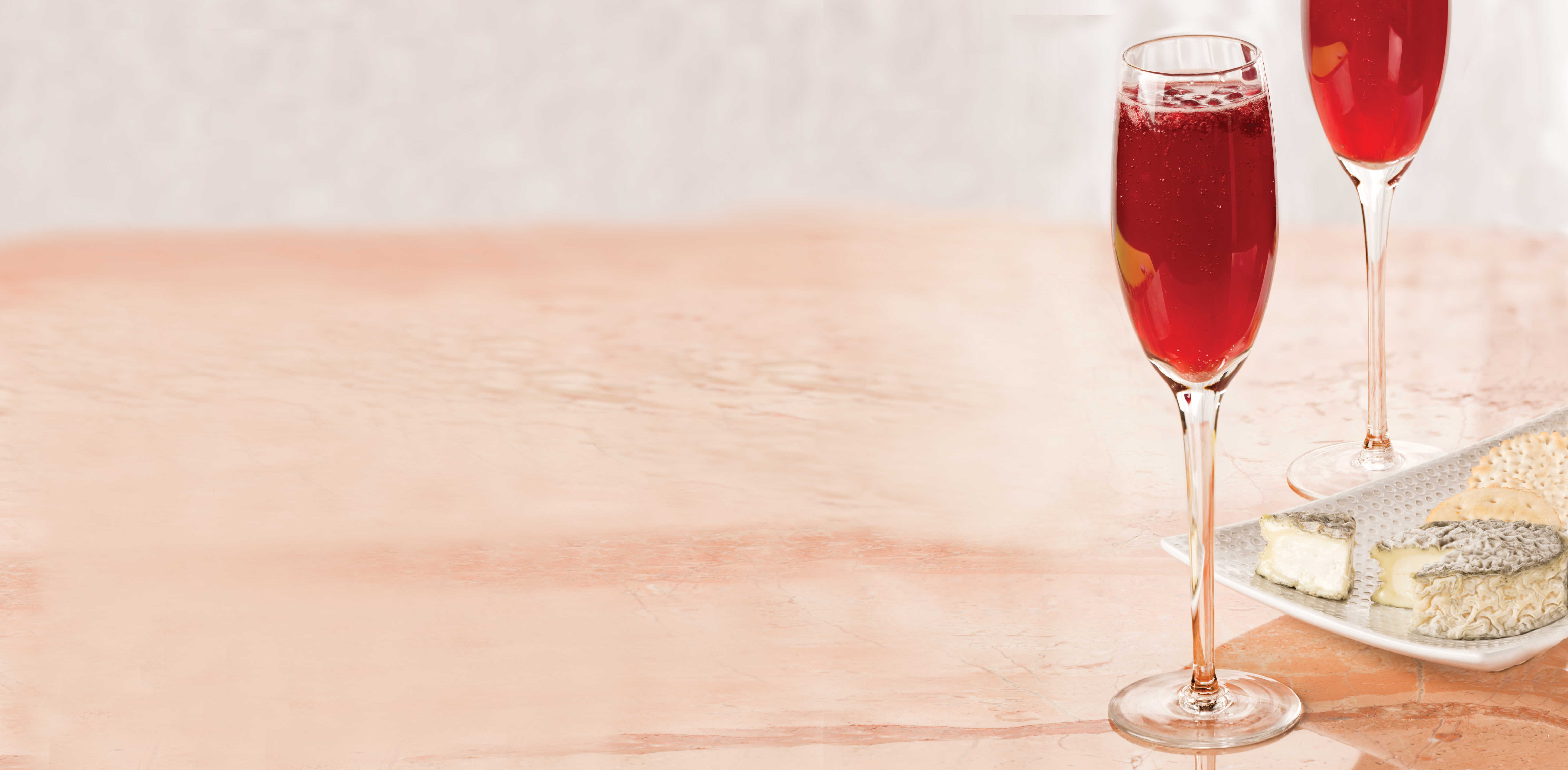 Campagne flute with pomegranate sparkler in it with a Vermont Creamery Bonne Bouche cheese to the side