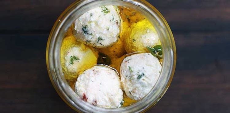 Oil and herb marinated balls of feta cheese in jar
