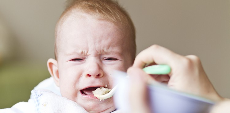 Baby cries while being fed from a spoon