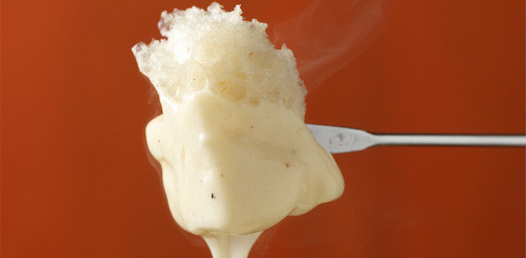 Bread on skewer with dripping fondue cheese melting off it