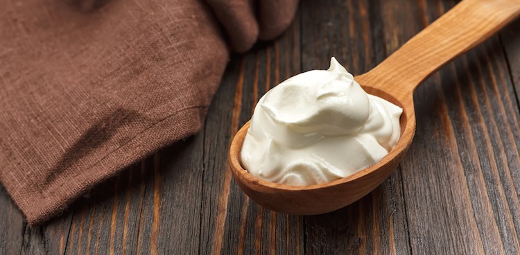 Crème Fraîche in a wooden spoon on a wooden board