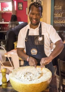 A server stirs tagliolini in a wheel of Grana Padano tableside at The Cousins Trattoria