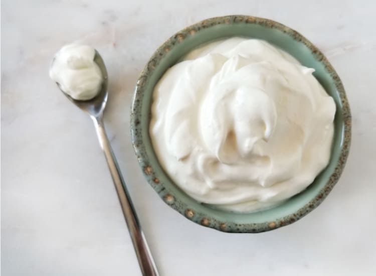 a spoon next to a bowl of homemade sour cream