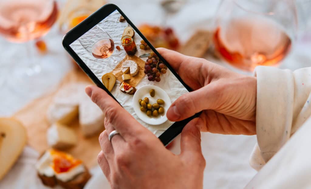 Image of cellphone taking photo of cheeseboard.