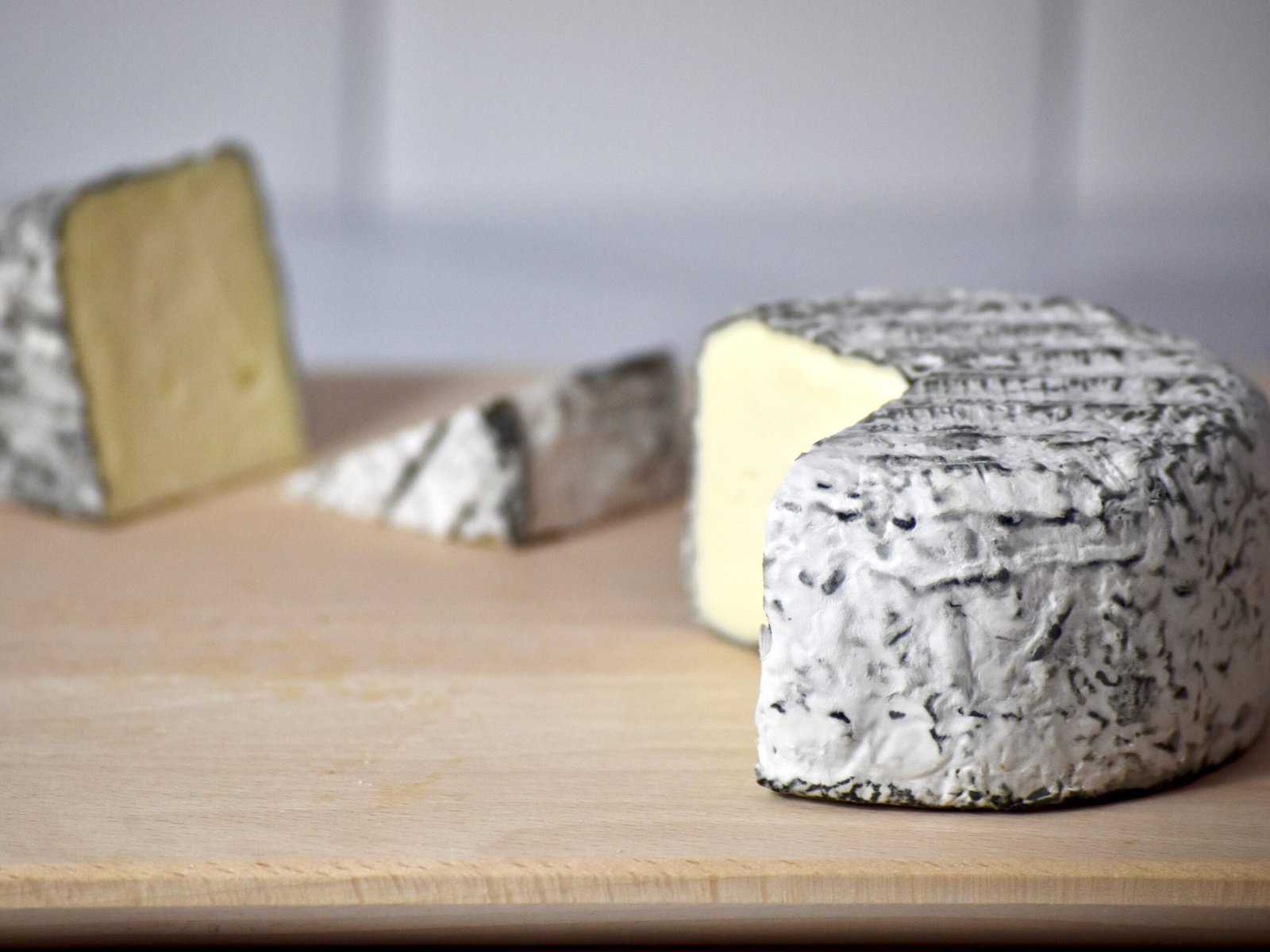 Ash-laden cheese from Jasper Hill on a wooden surface.