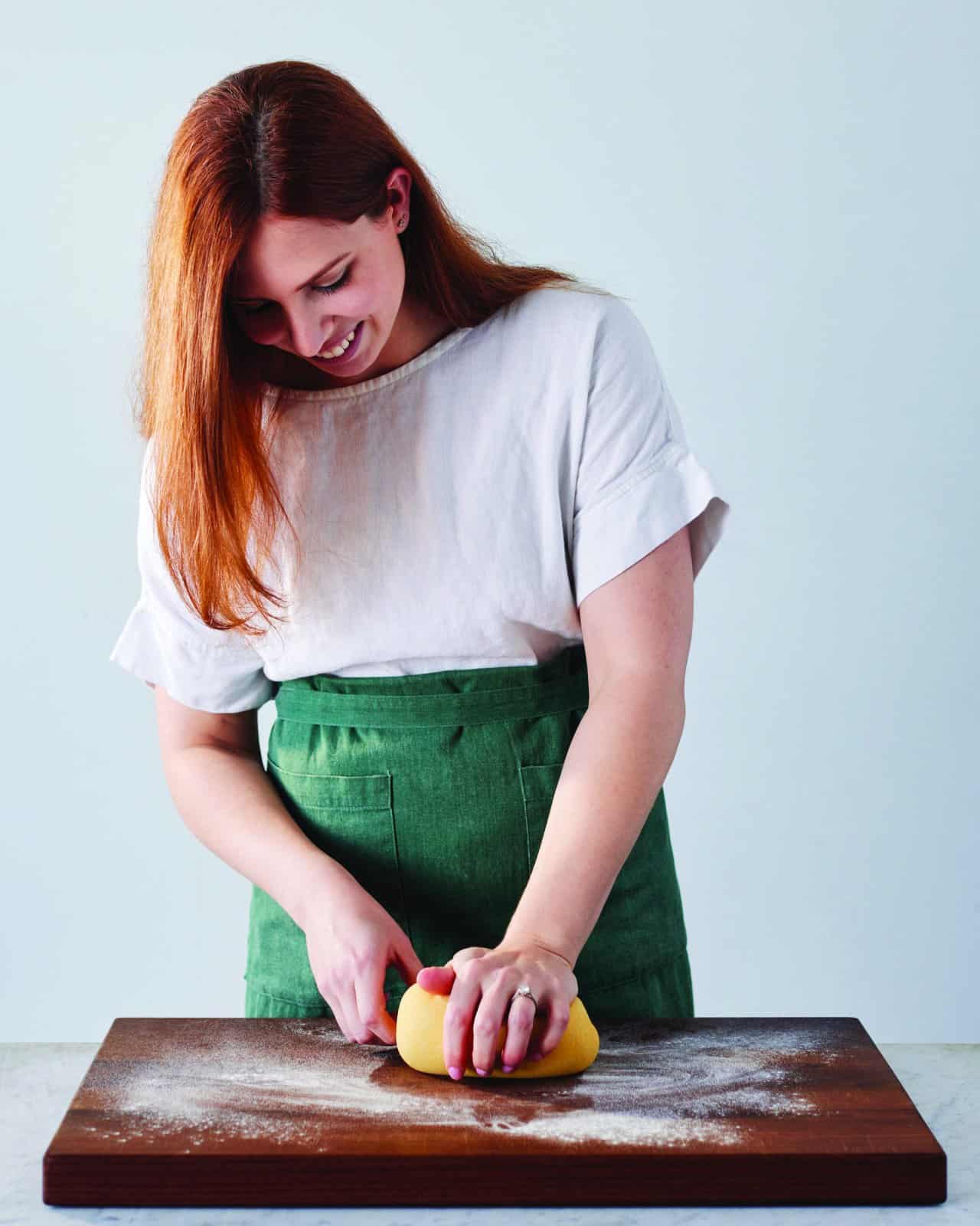 A woman kneads pasta dough.